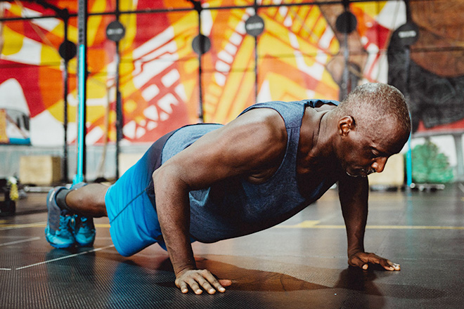 Black man doing push ups on gym floor